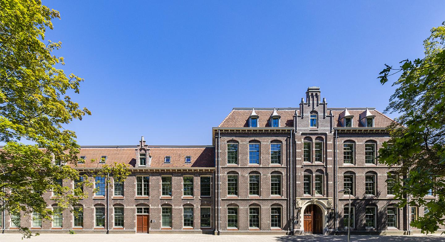 De karakteristieke monumentale gevel van de Mauritskazerne in Ede met rode dakpannen en bakstenen architectuur